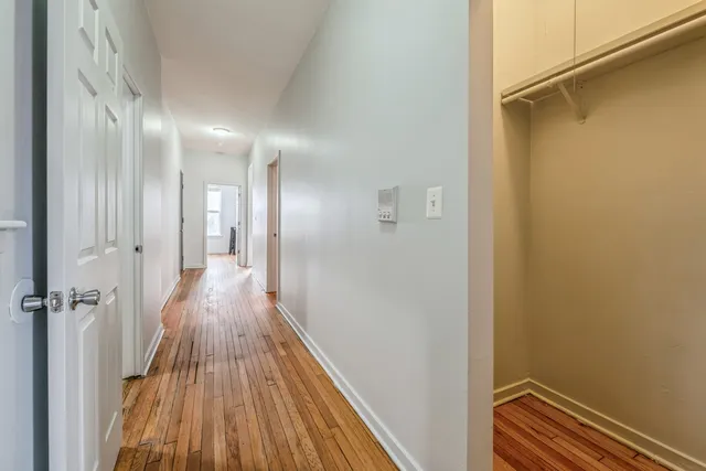 a view of a hallway with wooden floor and a bathroom
