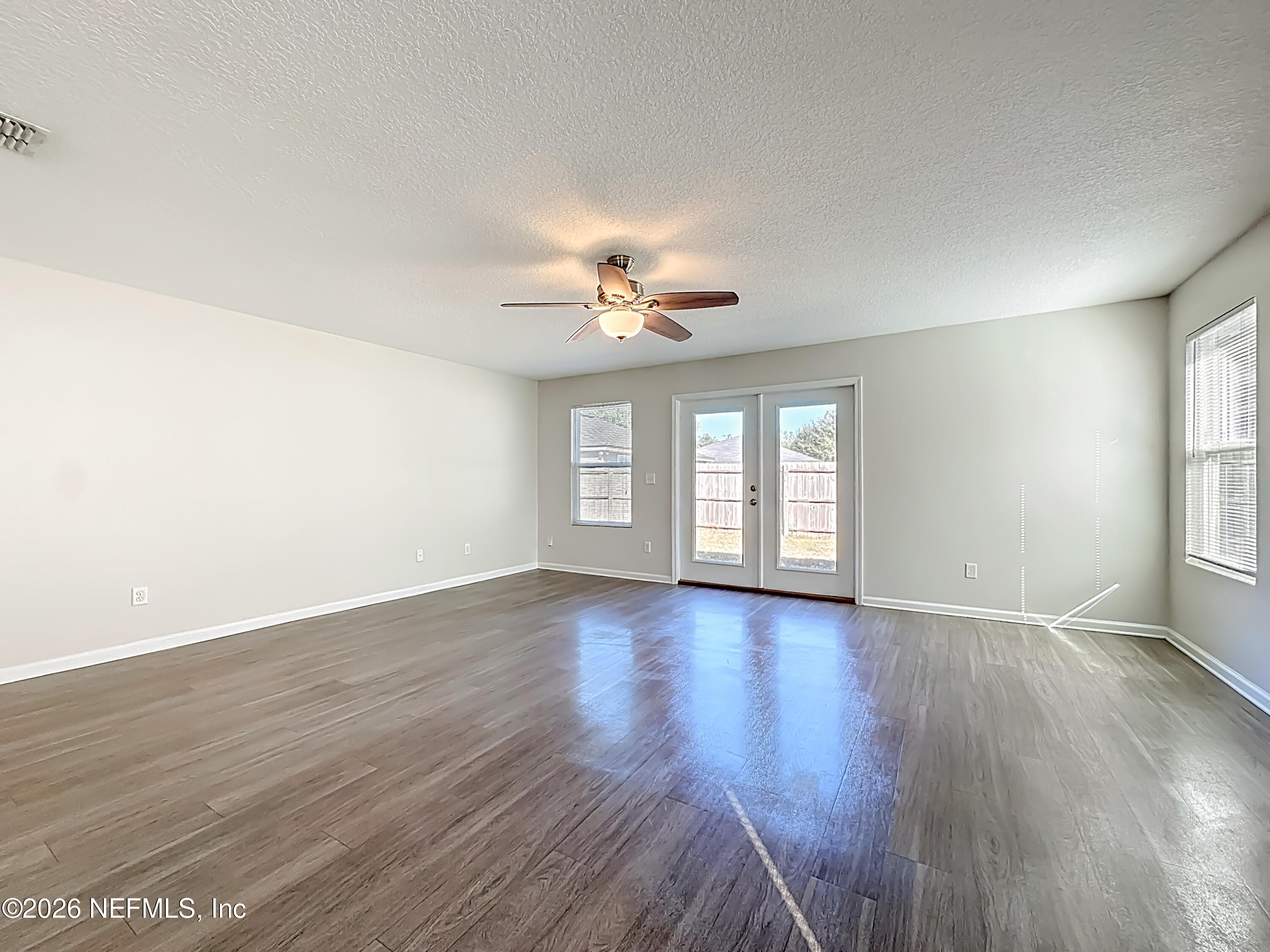 9487 Thorn Glen Road Jacksonville, FL 32208 - Photo 6 of 19 an empty room with wooden floor and windows