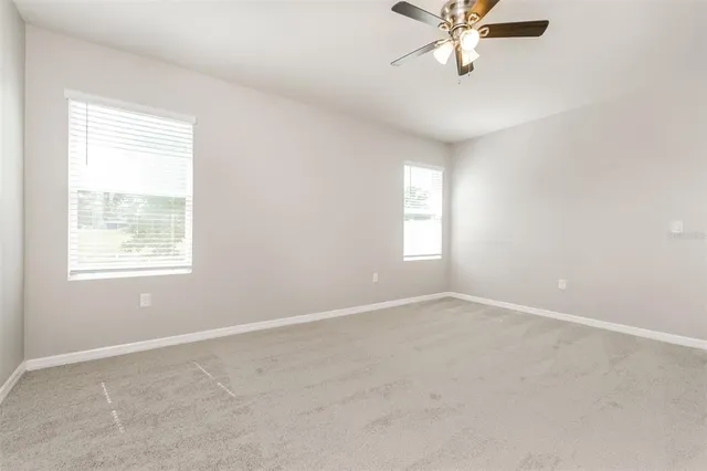 an empty room with windows and fan