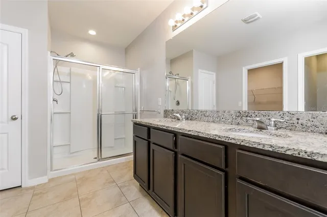 a bathroom with a granite countertop sink a mirror and a shower