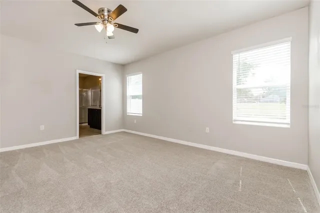 an empty room with windows and fan