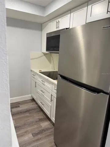 a kitchen with a refrigerator and white cabinets