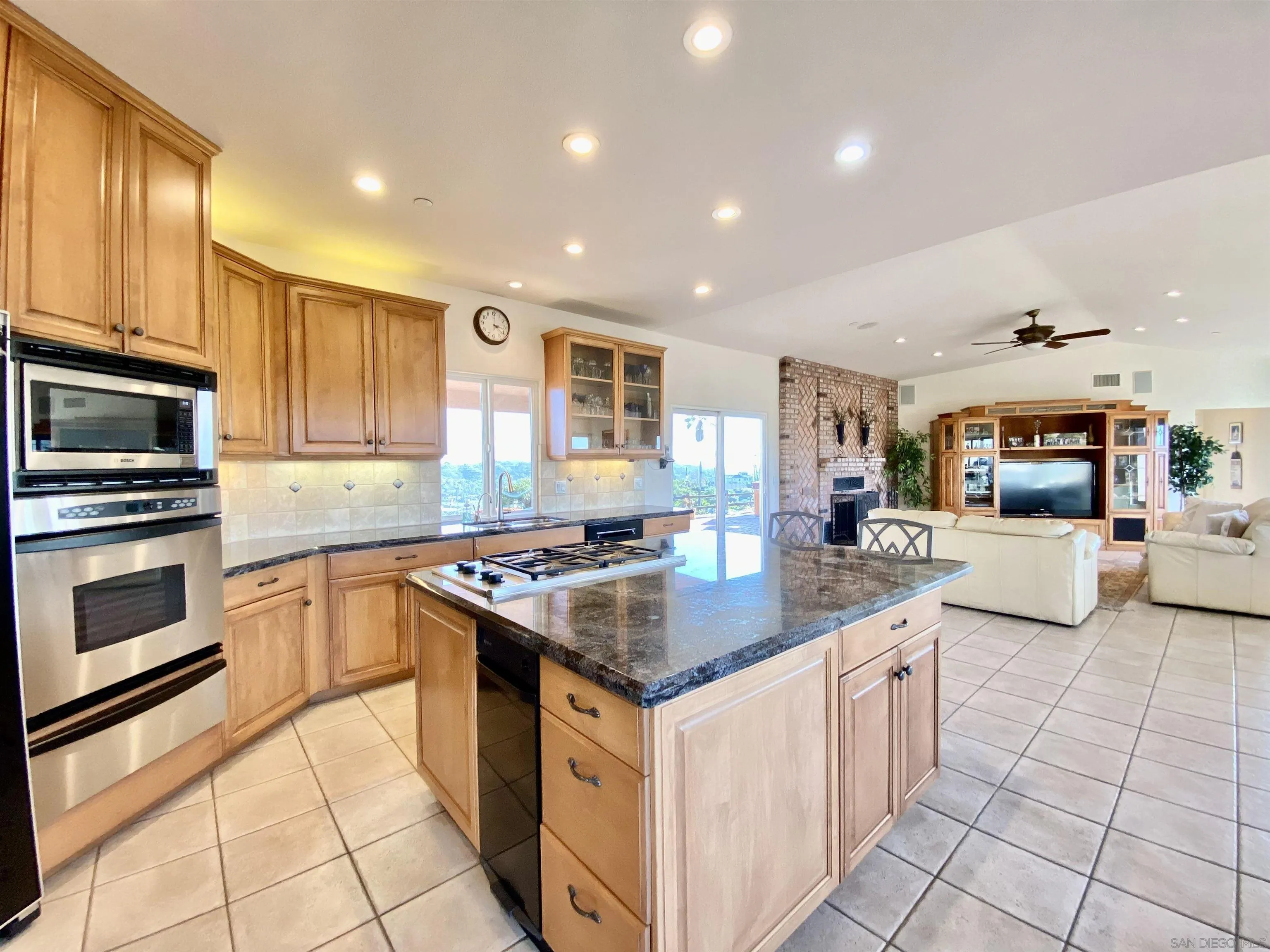 4375 North Rogers Road Spring Valley, CA 91977 - Photo 9 of 34 a kitchen with stainless steel appliances granite countertop a stove top oven a sink dishwasher a dining table and chairs with wooden floor