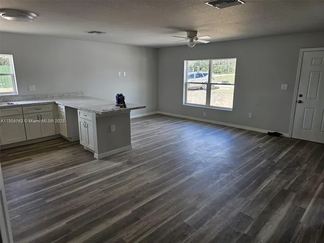 an empty room with wooden floor windows and ceiling fan