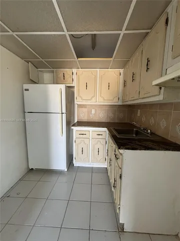 a kitchen with a white cabinets a refrigerator and a stove