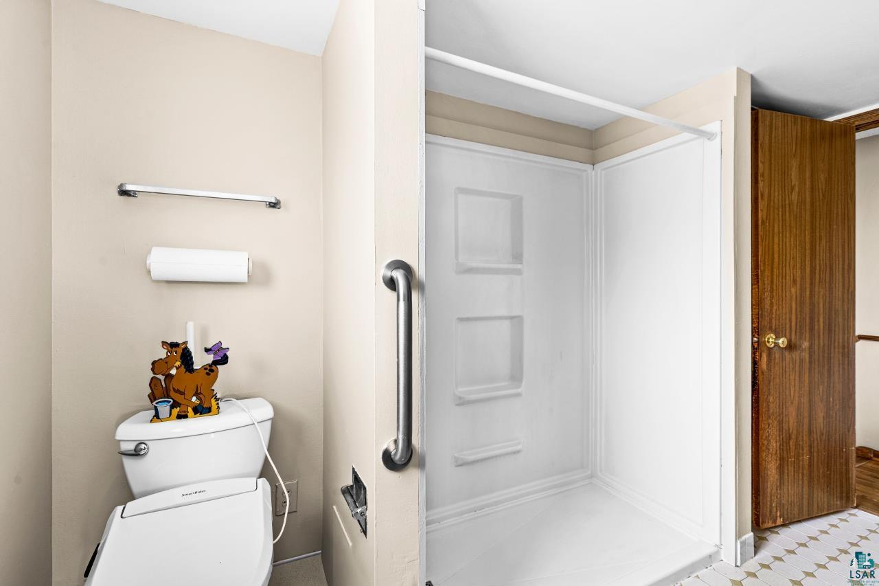 6606 Metso Road Kettle River, MN 55757 - Photo 16 of 84 White shower stall with built-in shelving, chrome grab bar, and neutral-toned walls