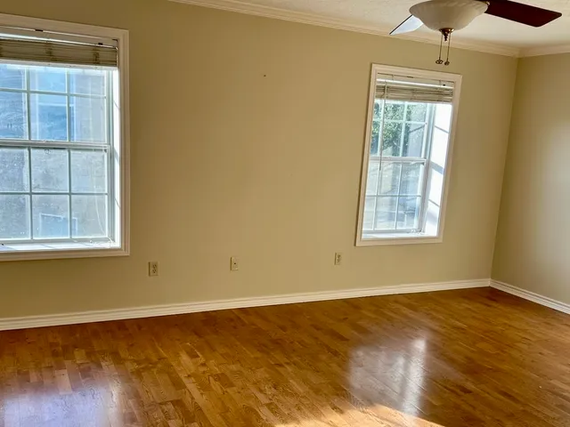 a view of an empty room with wooden floor and a shower