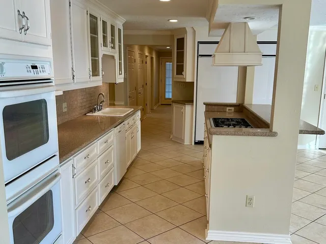 a kitchen with granite countertop a sink stove and cabinets
