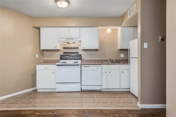 a kitchen with cabinets appliances and a wooden floor