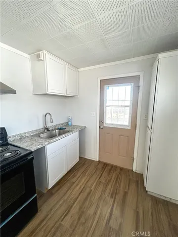 a kitchen with granite countertop a stove a sink and a refrigerator