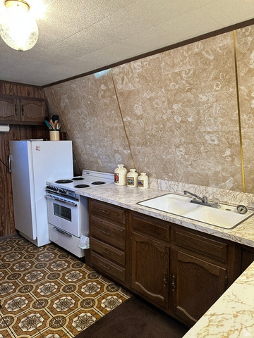 1085 West Elk Road Helper, UT 84526 - Photo 4 of 40 Kitchen featuring wood-finish cabinetry, laminate countertops, and a white drop-in sink with a chrome faucet