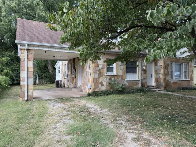 a view of a house with a yard and large tree