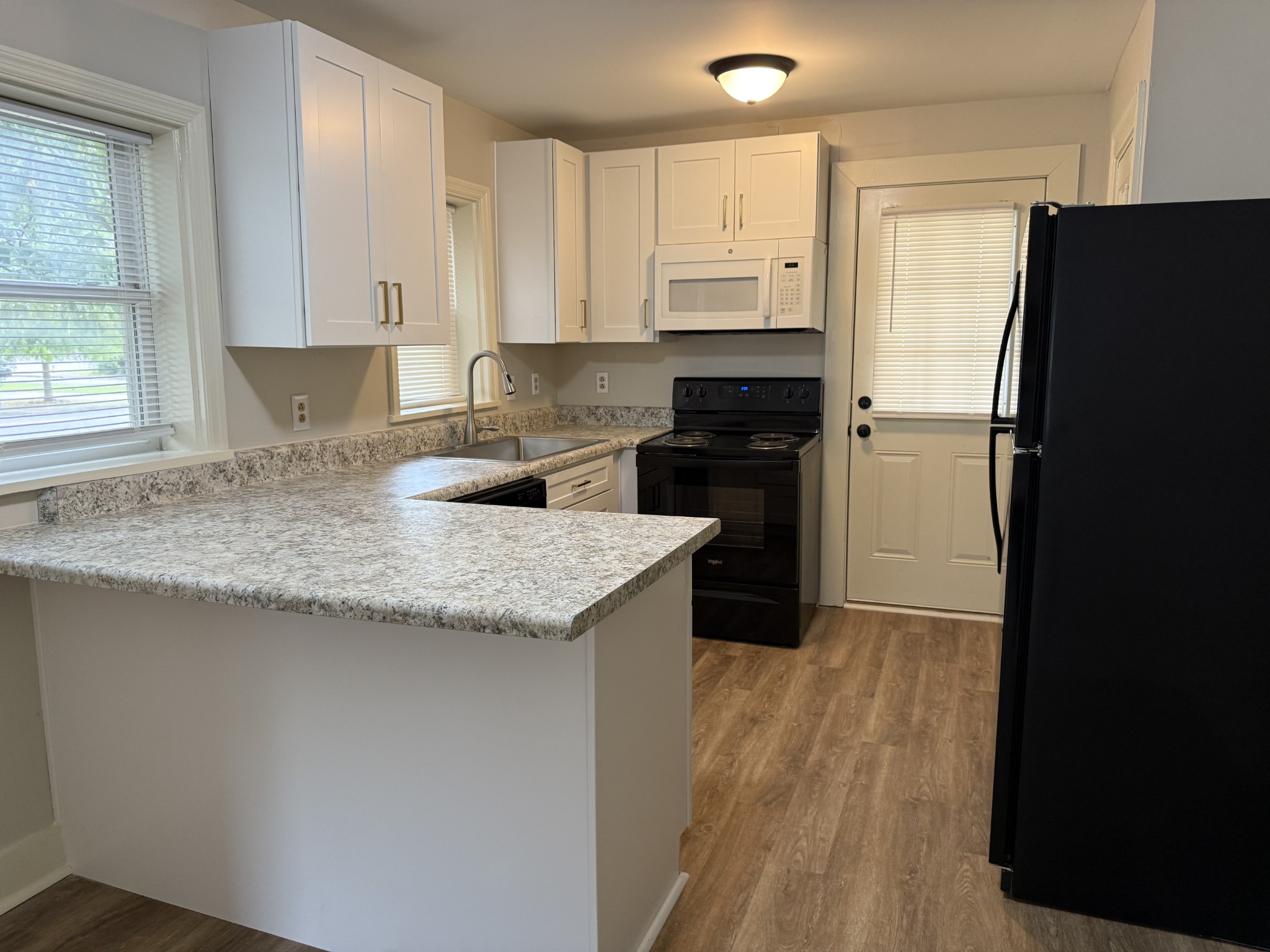428 2nd Avenue, Unit A Murfreesboro, TN 37130 - Photo 4 of 10 a kitchen with granite countertop a refrigerator a stove a sink and white cabinets with wooden floor