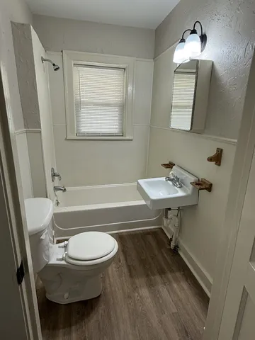a bathroom with a sink a toilet a mirror and shower