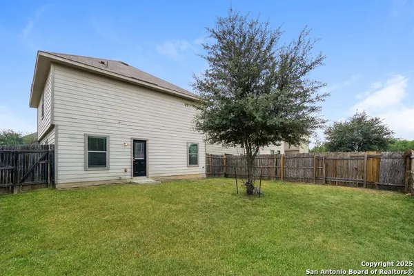 a backyard of a house with plants and wooden fence