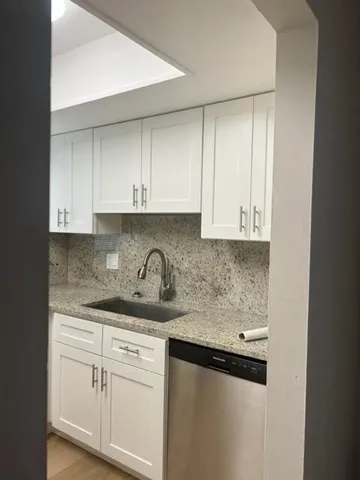 a kitchen with granite countertop white cabinets and a sink