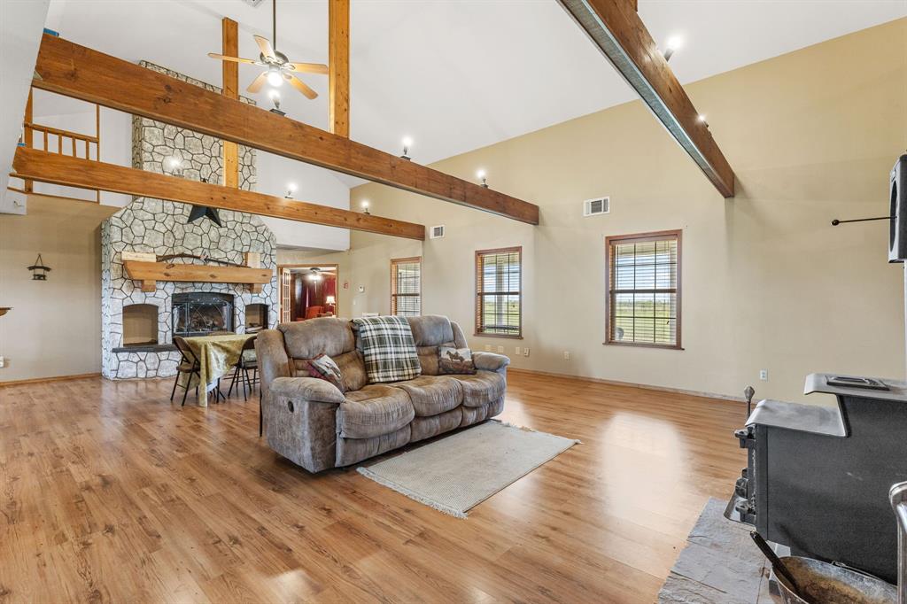 13315 Highway 281 Scotland, TX 76379 - Photo 6 of 40 Spacious living area featuring an impressive fireplace, exposed ceiling beams, ceiling fans, and multiple windows