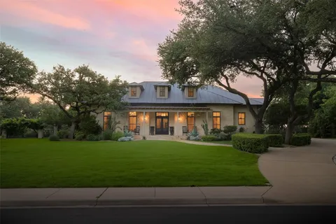 a view of a big yard in front of a brick house with large windows