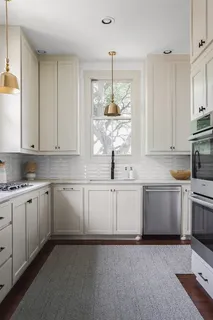a kitchen with kitchen island granite countertop white cabinets white stainless steel appliances with a sink and dishwasher