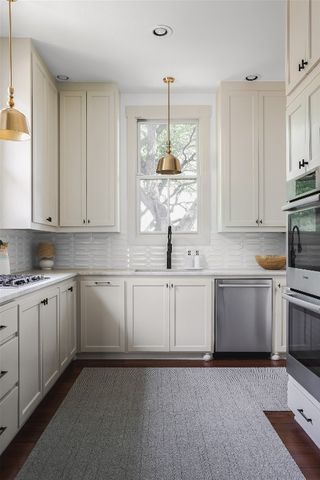 a kitchen with kitchen island granite countertop white cabinets white stainless steel appliances with a sink and dishwasher