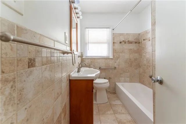 a bathroom with a granite countertop bathtub shower sink vanity and toilet