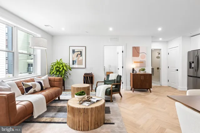 a living room with furniture kitchen view and a large window