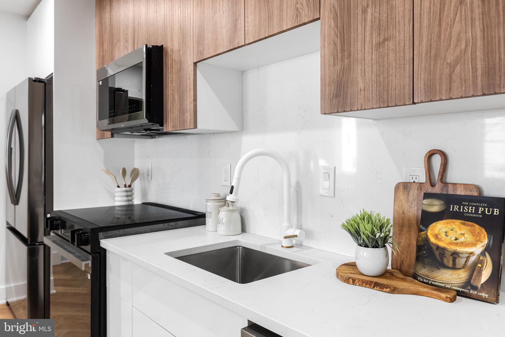 1124 Florida Street Northeast, Unit 210 Washington, DC 20002 - Photo 6 of 26 a kitchen with a sink and a stove top oven with wooden floor