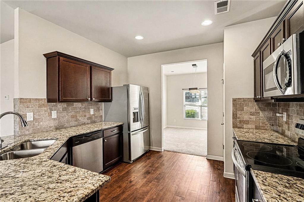 11046 Genova Terrace Hampton, GA 30228 - Photo 14 of 38 a kitchen with granite countertop a refrigerator stove and sink