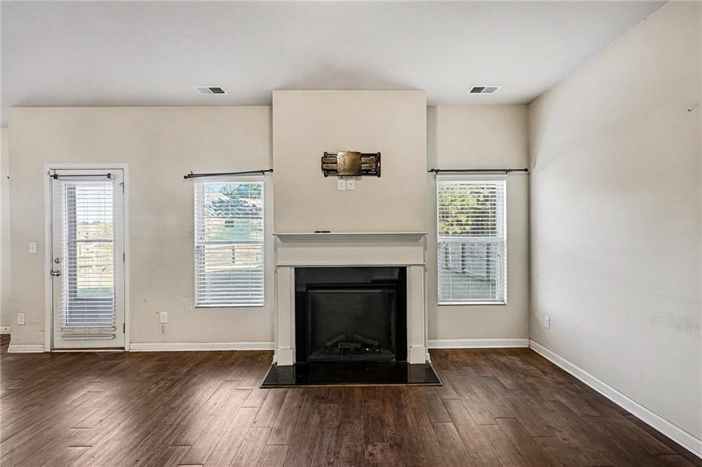 11046 Genova Terrace Hampton, GA 30228 - Photo 6 of 38 an empty room with wooden floor fireplace and windows