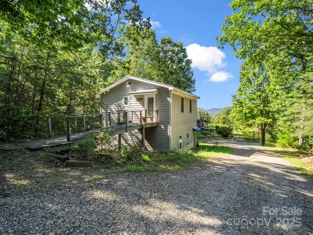 a view of a small yard in front of a house with large trees