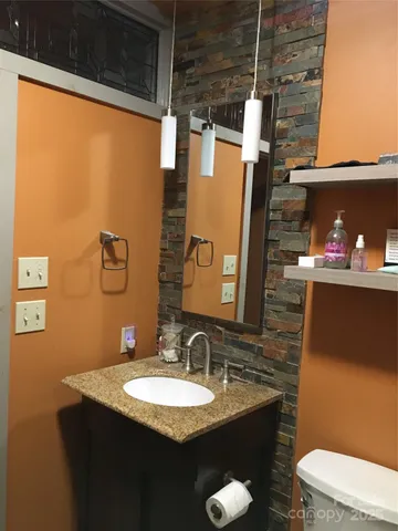 a bathroom with a granite countertop sink toilet and mirror