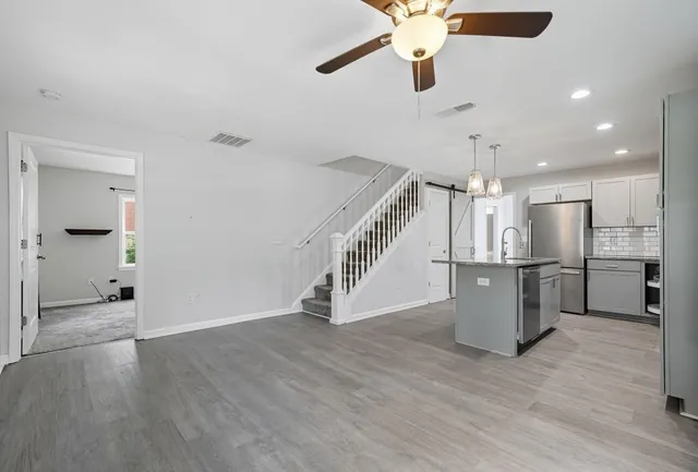a view of a hallway with wooden floor and a kitchen