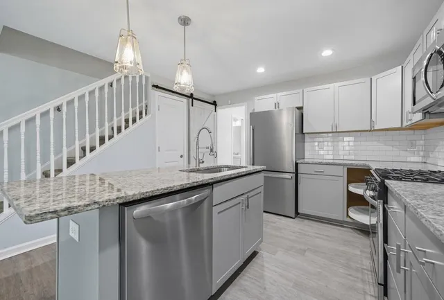 a kitchen with granite countertop kitchen island stainless steel appliances a sink a counter top space cabinets and a chandelier