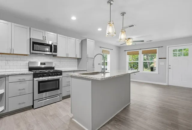 a kitchen with stainless steel appliances granite countertop a stove a sink and a microwave