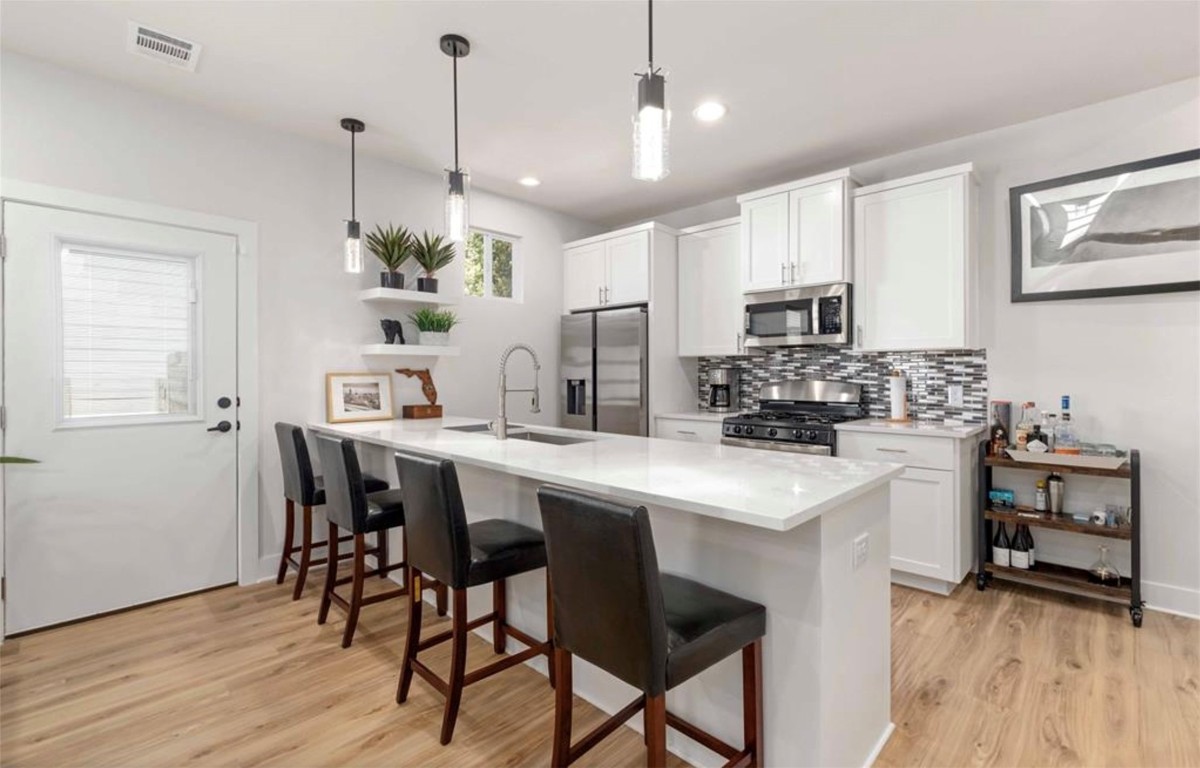 7407 Bethune Avenue, Unit 2 Austin, TX 78752 - Photo 9 of 30 a kitchen with kitchen island a dining table chairs stainless steel appliances and wooden floor