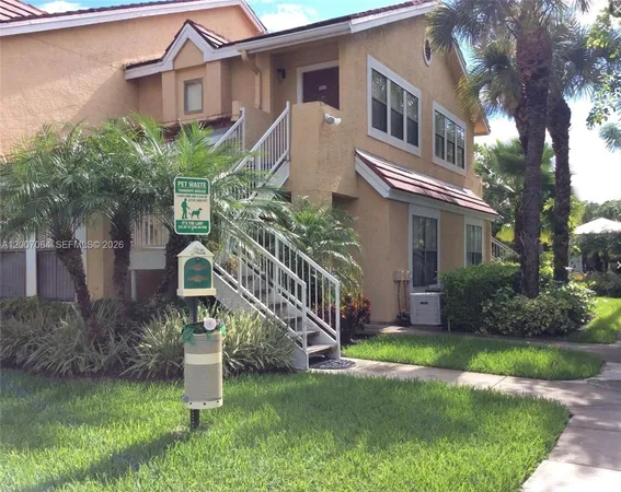 a front view of a house with a garden and tree