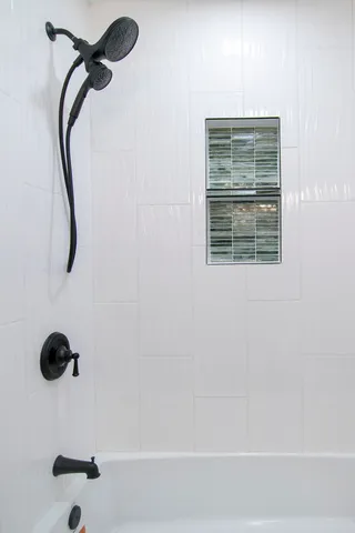 a bathroom with a bath tub a shower and a window