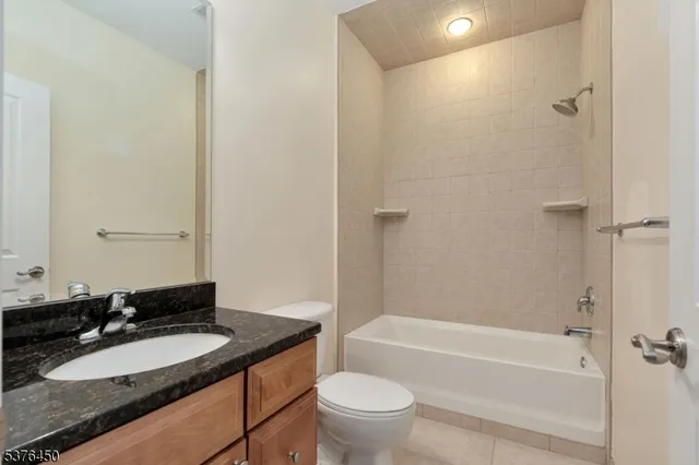 a bathroom with a granite countertop sink toilet mirror and bathtub