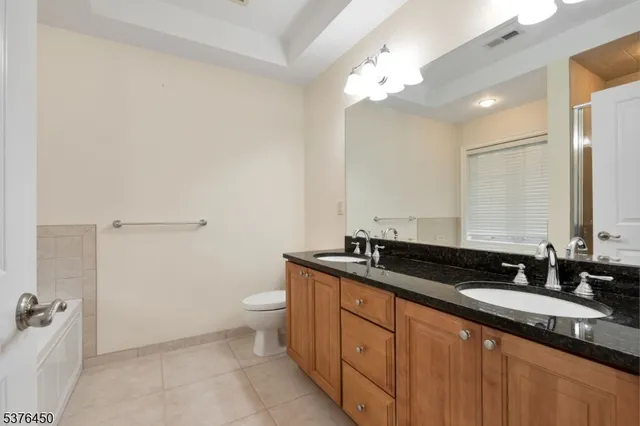 a spacious bathroom with a granite countertop sink a toilet a mirror and bathtub