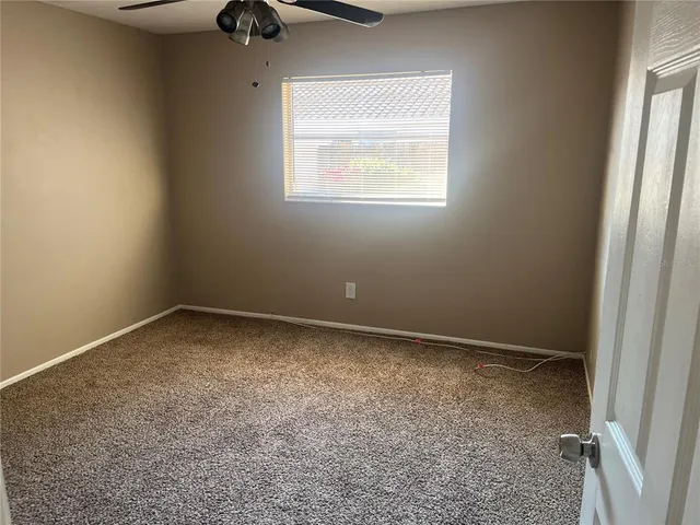 an empty room with a window and a fan
