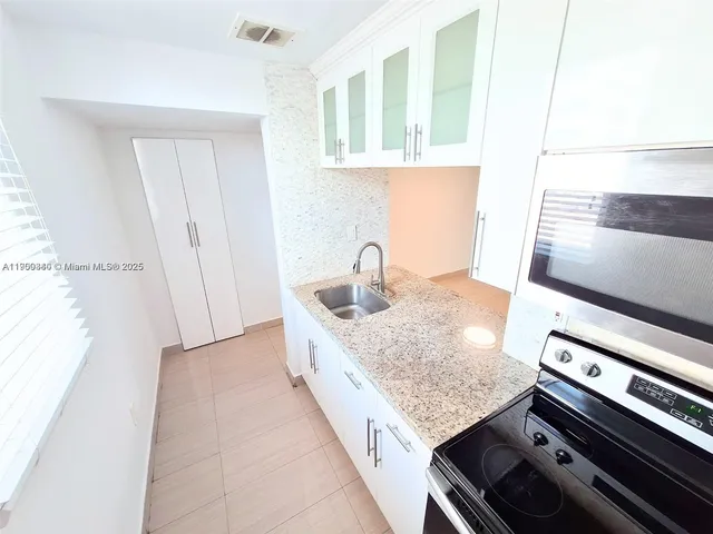 a kitchen with stainless steel appliances granite countertop a sink a microwave a refrigerator and a stove