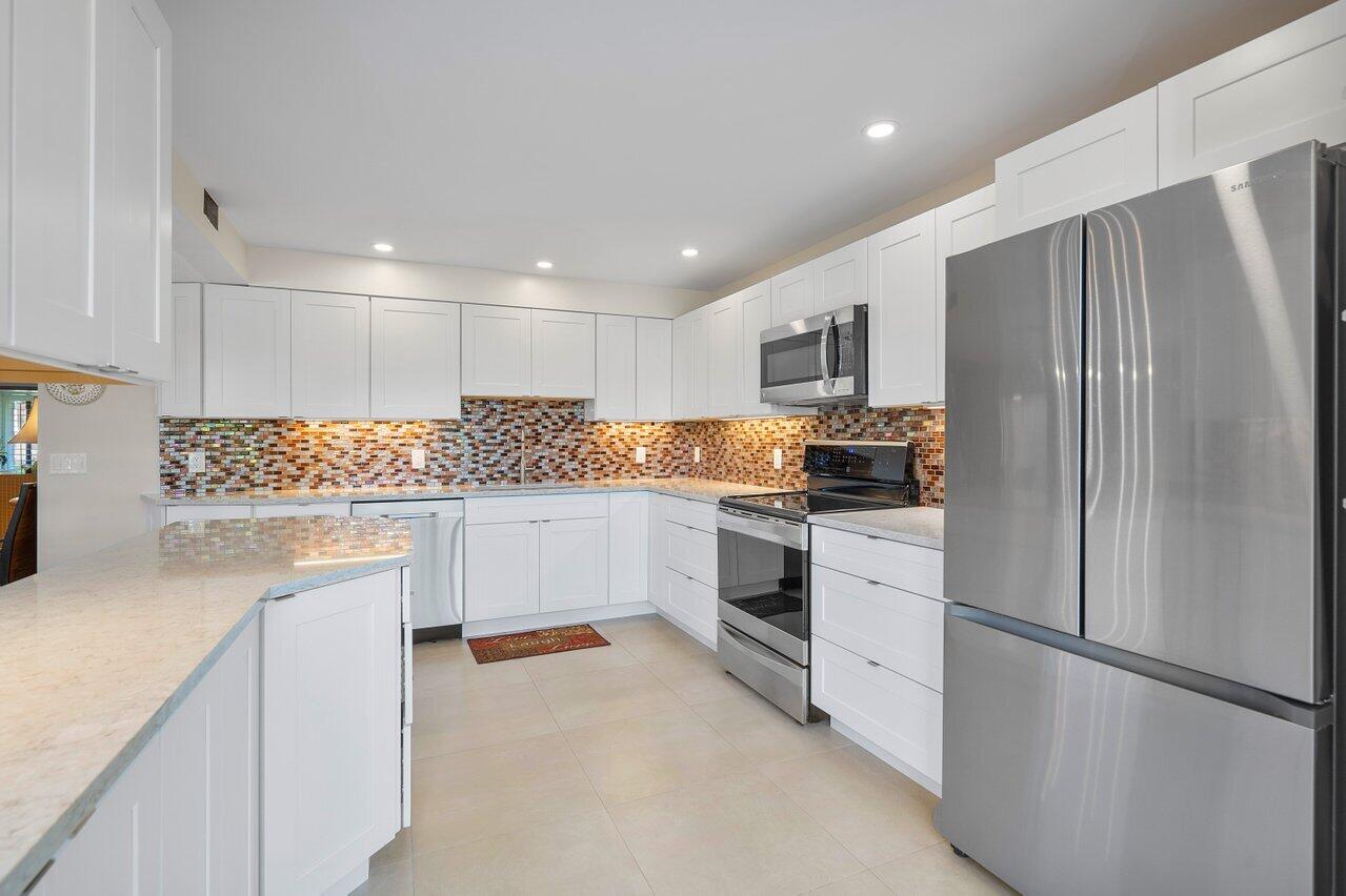 3677 Quail Ridge Drive, Unit BOBWHITE B Boynton Beach, FL 33436 - Photo 15 of 47 a kitchen with white cabinets and stainless steel appliances
