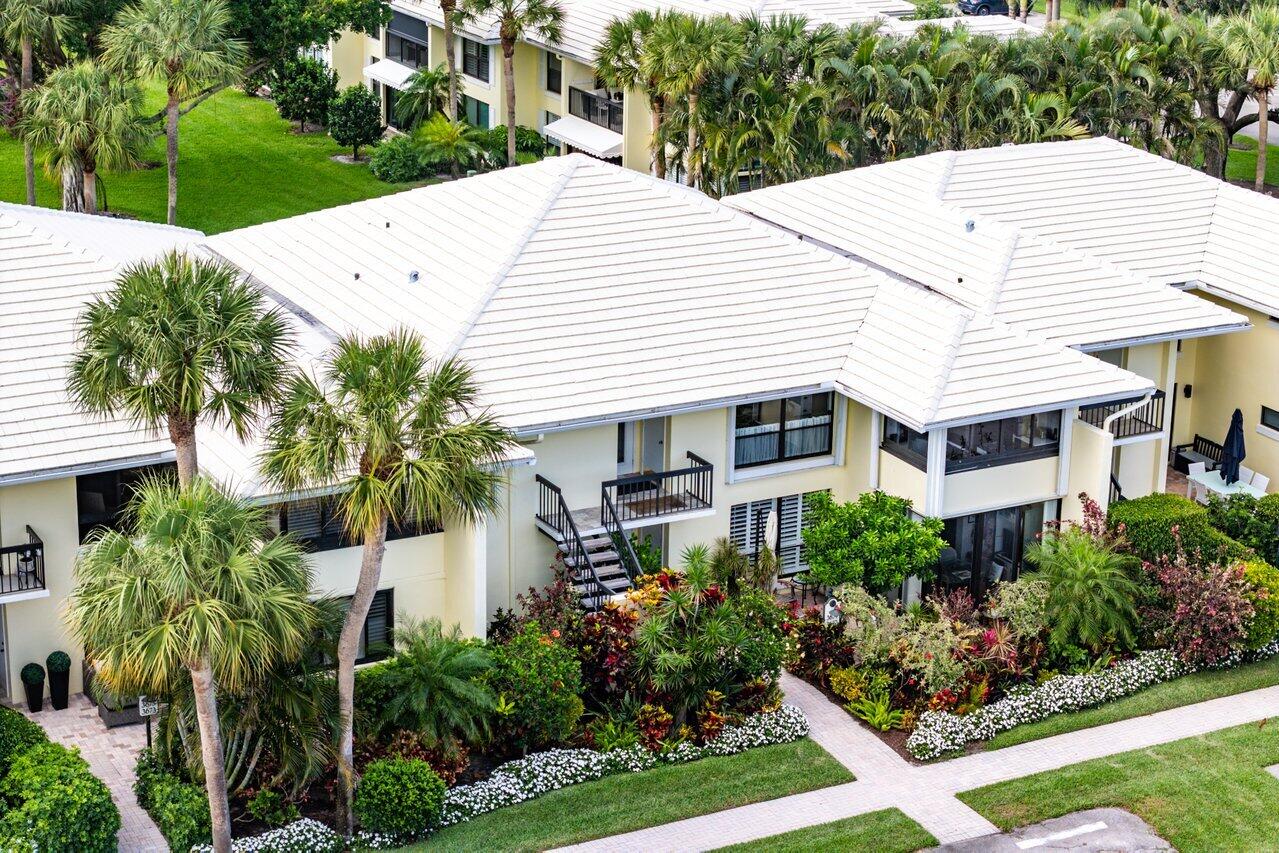 3677 Quail Ridge Drive, Unit BOBWHITE B Boynton Beach, FL 33436 - Photo 27 of 47 a view of a white house with a yard and potted plants