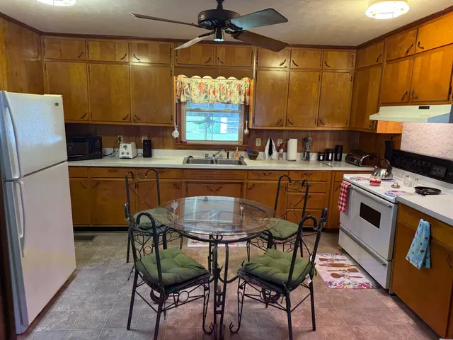 a kitchen with stainless steel appliances a table chairs refrigerator and a sink
