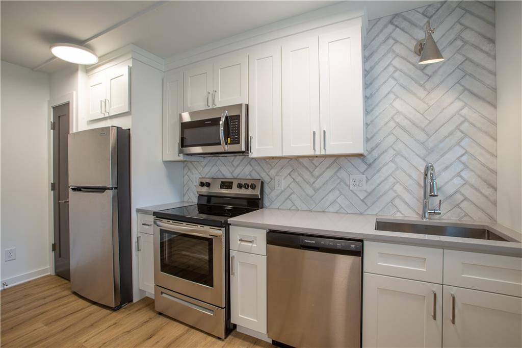 41 25th Street Northwest, Unit 5 Atlanta, GA 30309 - Photo 5 of 15 a kitchen with stainless steel appliances white cabinets white stove a sink and dishwasher