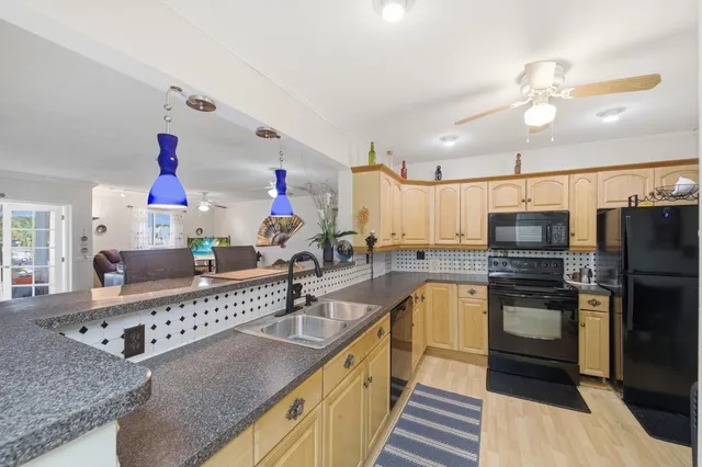 a kitchen with stainless steel appliances granite countertop a refrigerator a stove a sink a stove a dining table and chairs with wooden floor