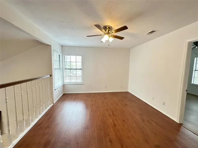 a view of empty room with wooden floor and fan