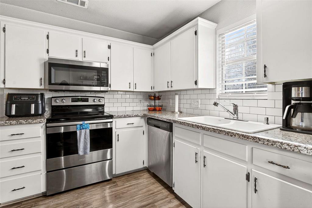 1001 South 4th Street Bonham, TX 75418 - Photo 11 of 27 a kitchen with granite countertop cabinets stainless steel appliances and a window