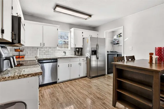 a kitchen with stainless steel appliances kitchen island granite countertop a sink dishwasher stove and refrigerator with wooden floor