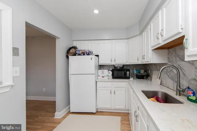a kitchen with a refrigerator sink and white cabinets